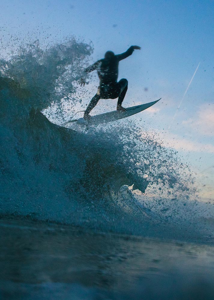 Surfer at sunrise doing and aerial maneuver